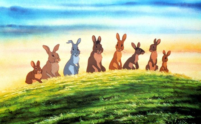 A scene from the film Watership Down. Rabbits are lined up on a hill.